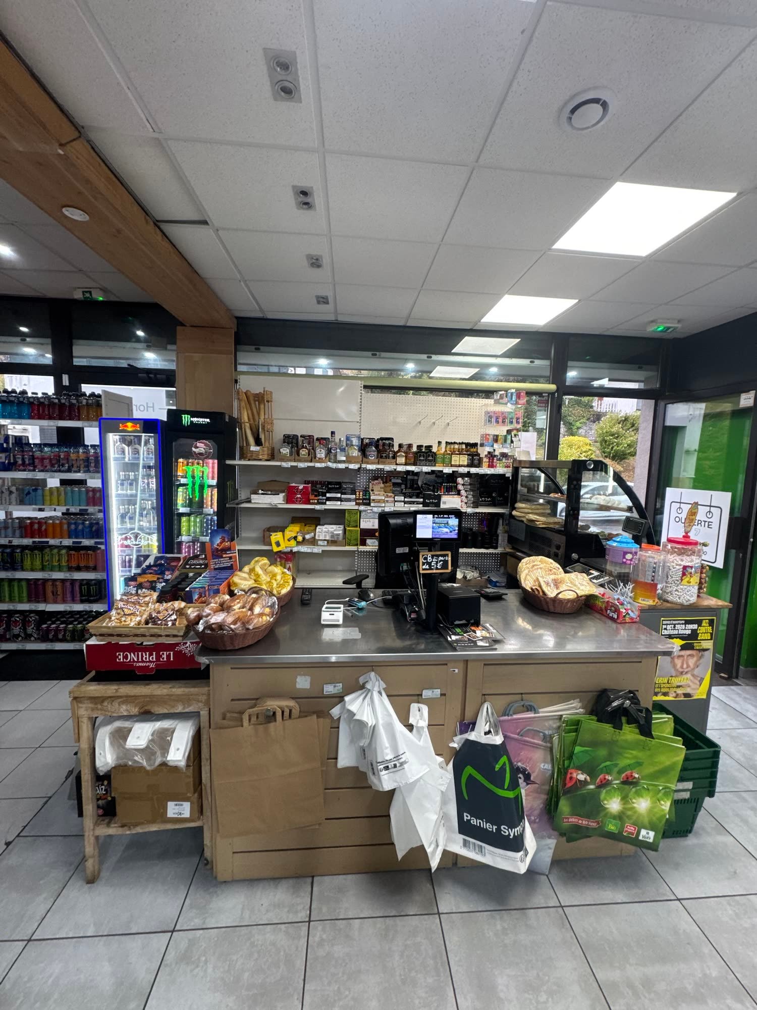 La caisse à l'entrée, face à la porte, avec le sac Panier Sympa et les viennoiseries